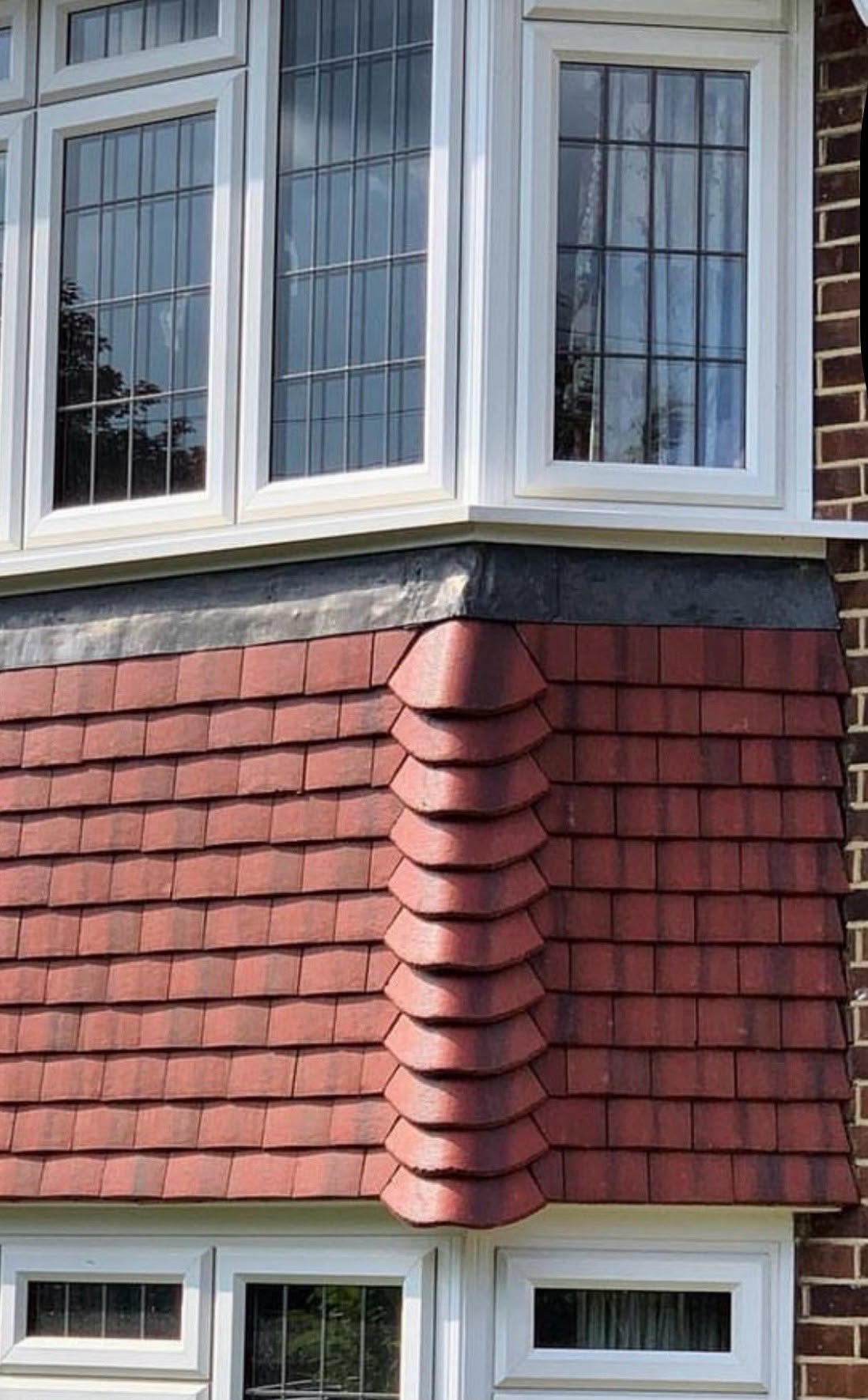 Red plain tiles on a bay window with a lead flashing above