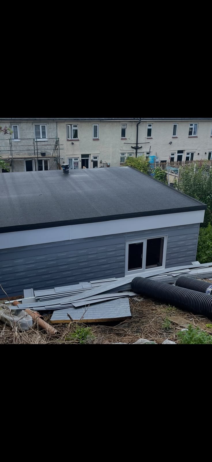 Flat roofed extension with a smooth grey finish and grey cladding