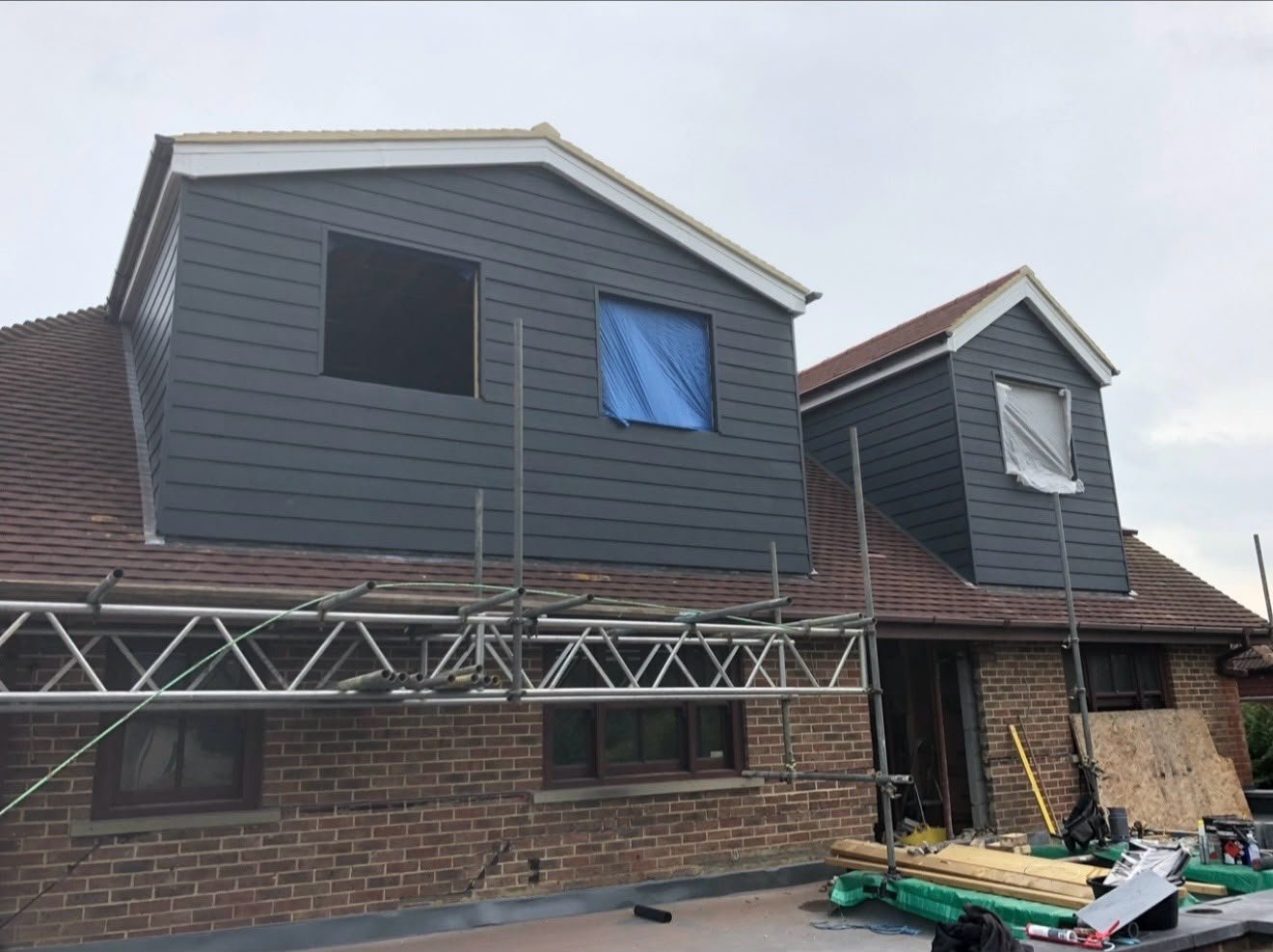 Two grey clad dormers under construction with scaffolding in front